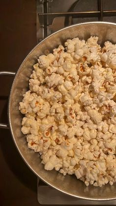 a metal pan filled with popcorn sitting on top of a stove