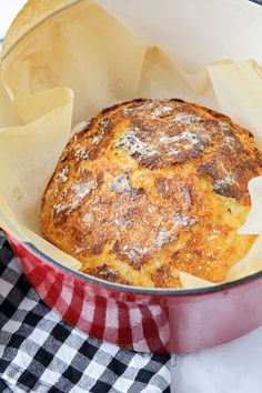 a baked item in a red pan on a checkered table cloth next to a black and white napkin