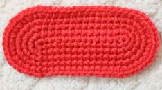 a crocheted red object laying on a white surface