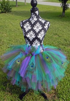 a mannequin in the grass with peacock feathers on it