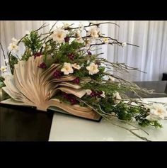 an open book sitting on top of a table covered in flowers