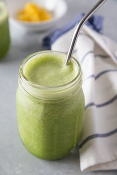 a green smoothie in a glass jar with a spoon sticking out of the top