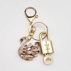 a gold key chain with a lock on it and a bird charm attached to it