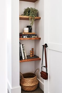 an open book shelf with books and plants on it, next to a wicker basket