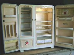 three open refrigerators sitting next to each other on a wooden table with black background