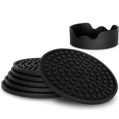 four black rubber coasters with holes on the bottom and one has a cup holder