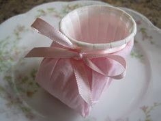 a small pink basket with a bow on it sitting on a white and floral plate