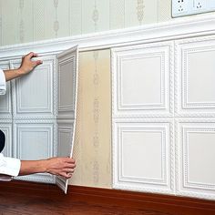 a man kneeling on the floor in front of a wallpapered paneling pattern