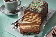 a piece of chocolate cake with sprinkles next to a cup of coffee