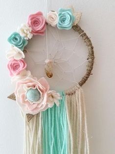 a dream catcher with flowers and feathers hanging on the wall