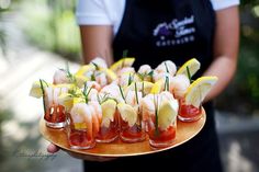 a person holding a platter with appetizers and lemon wedges on it