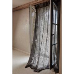 an open window in the corner of a room with curtains hanging from it's sides