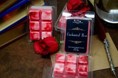 two wax cubes with rose petals in them on a table next to some books and a pen