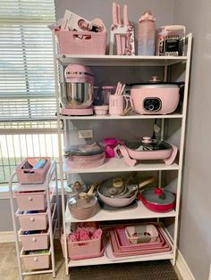 a shelf filled with lots of pink kitchenware and utensils on top of it