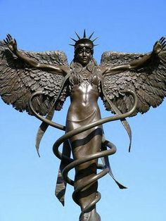 a statue with wings and snakes around it's neck on top of a building