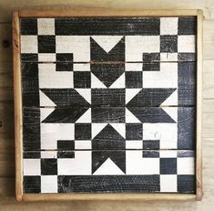 a black and white wooden wall hanging with an arrow pattern on the bottom half of it