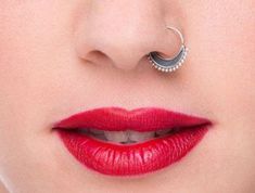 a woman with red lipstick and piercing on her nose