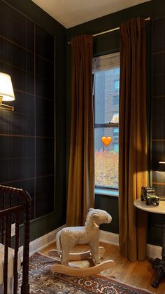 a rocking horse in the corner of a room with dark green walls and wood flooring