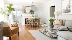 a living room filled with furniture next to a dining room table and two chairs on top of a hard wood floor