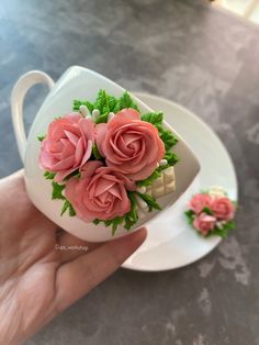 a hand holding a tea cup with pink flowers in it