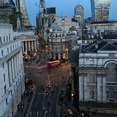 an aerial view of a city with tall buildings in the background at dusk, including a double decker bus