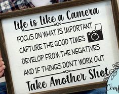 a person holding up a sign that says, life is like a camera focus on what is important capture the good times develop from the negatives and if things don't