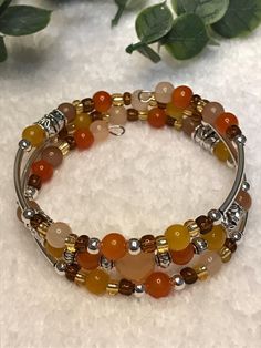 This is a 2 1/4 inches around by 1" tall, Harvest Collection, Brown, Orange, Yellow and Silver Tone, 3 Coil Memory Wire, Wrap Cuff Bracelet. I design each piece with you in mind. I put a lot of thought into my Jewelry. I love bling, I love sparkly flashy (but not too flashy) things. I like versatility, when creating my Jewelry I always try to consider outfit possibilities... so when I create my Jewelry pieces, I try to make them versatile to go with more than one outfit of that color. I take great pride in every piece of jewelry I make, and my personal goal is ALWAYS 100% SATISFACTION for my customers. So, rest assured you can purchase from me and know you are getting a beautiful, versatile, quality product made with sincere, heartfelt love, and quality!  Have a question? Please feel free Adjustable Wire Wrapped Beaded Bracelets, Adjustable Wire Wrapped Crystal Bracelet With Round Beads, Adjustable Stackable Round Beads Bangle, Adjustable Stackable Bangle With Round Beads, Stackable Adjustable Bangle With Round Beads, Adjustable Wire Wrapped Wrap Bracelet, Adjustable Wire Wrapped Wrap Bracelet Bangle, Spiritual Wire-wrapped Beaded Bracelets, Spiritual Wire Wrapped Beaded Bracelets