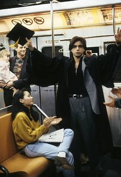 a man and woman on a subway train with their arms in the air as they look at each other