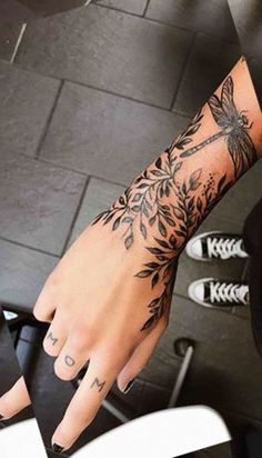 a woman's hand with tattoos on it and a flower tattoo on the wrist