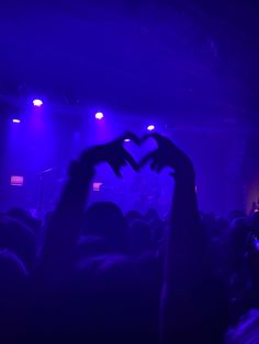 two hands making a heart with their fingers in front of a crowd at a concert