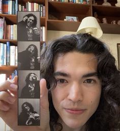 a man holding up an image of himself in front of bookshelves and shelves