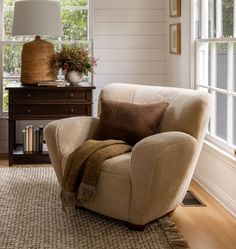 a living room with a chair, table and lamp in it's centerpiece