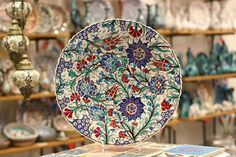 there are many plates on display in the store, including one with an elaborately decorated design