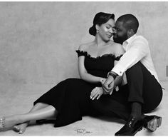 a black and white photo of a man and woman sitting on the floor hugging each other