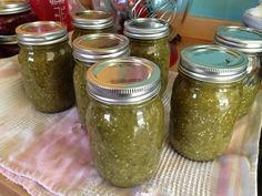 four jars filled with pickles sitting on top of a table next to other items