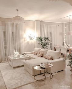 a living room filled with white furniture and lots of plants on the wall next to it