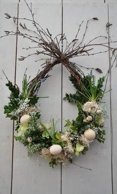 a wreath hanging on the side of a wooden wall with white flowers and greenery