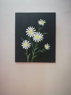 a painting of white daisies on a black square with yellow centers and green stems