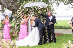 a bride and groom kiss under an umbrella as they walk down the aisle to their wedding ceremony