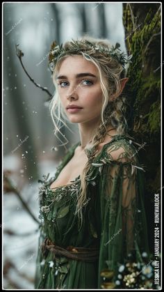 a woman dressed in green is standing next to a tree with leaves on her head