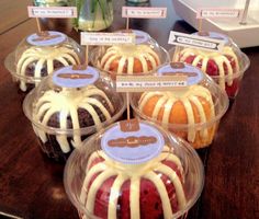 there are many desserts in plastic containers on the table with name tags attached to them