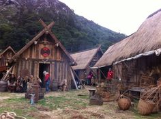 people are standing in front of huts with thatched roofs and straw baskets on the ground