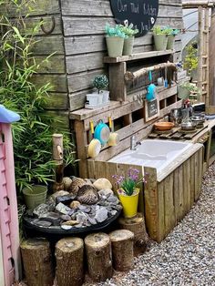 an outdoor kitchen with potted plants and pots on the outside, next to a garden shed