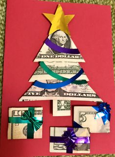 a christmas tree made out of money on top of a pink paper sheet with ribbons