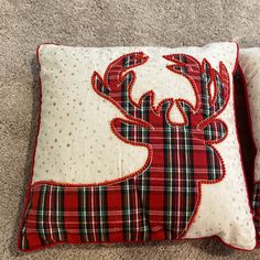 two red and white decorative pillows on the floor, one with a deer's head