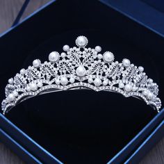 a tiara in a box with pearls on the sides and beads at the top