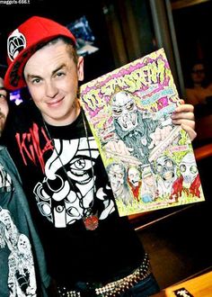 two men standing next to each other at a bar holding up a comic book with cartoon characters on it