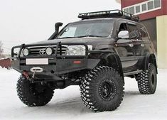 a black four - doored vehicle parked in front of a building on snow covered ground