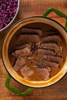 pot roast with gravy and red cabbage next to it on a wooden table