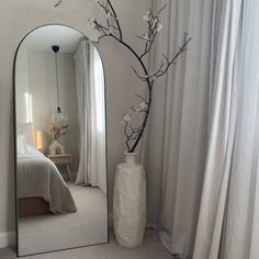 a white vase sitting next to a mirror on top of a carpeted room floor